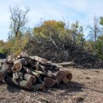 Muž čistí zarastený terén pomocou krovinorezu a iného náradia na odstránenie prekážok.