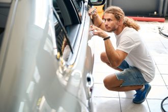 Odborník opravuje preliačinu na karosérii automobilu po poškodení vandalizmom.
