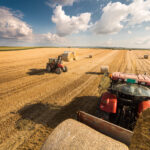 Traktor a pracovná štvorkolka pri práci na väčšom pozemku.