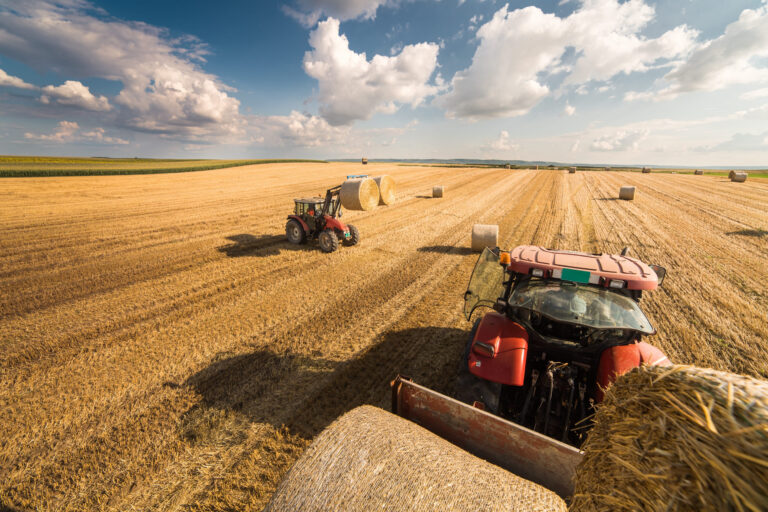 Traktor a pracovná štvorkolka pri práci na väčšom pozemku.