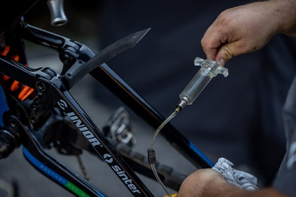Detail odvzdušňovania hydraulických bŕzd bicykla pomocou striekačky a hadičky.