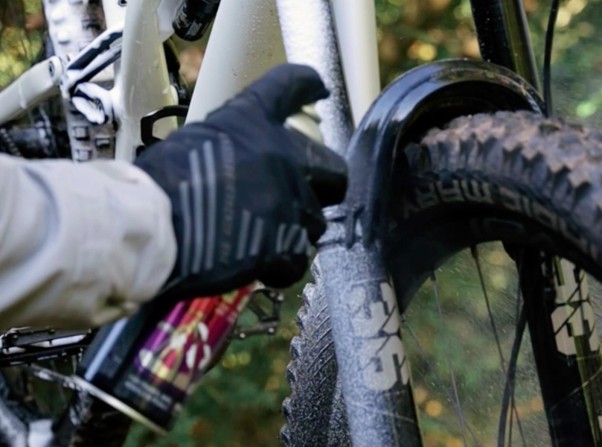 Údržba bicykla pomocou červenej servisnej kefy na odstránenie nečistôt z pohyblivých častí.